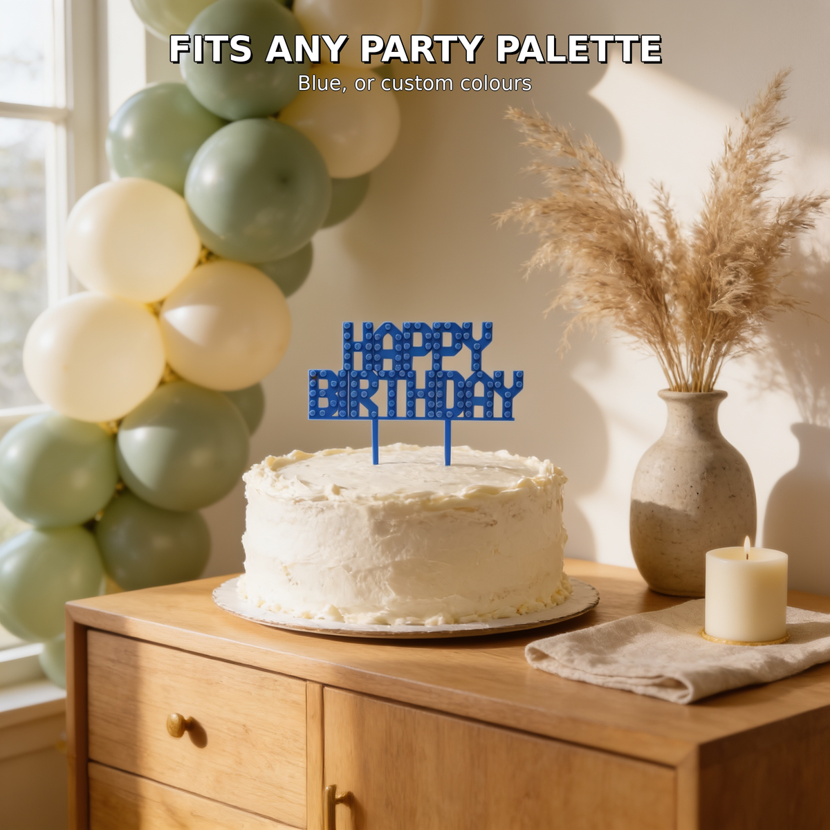 Blue brick cake topper on a birthday cake in a warm boho scene with pampas grass and sage balloons