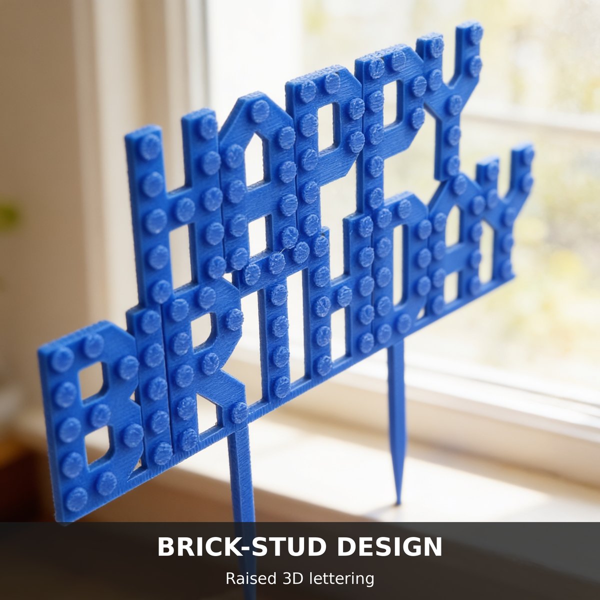 Macro close-up of raised brick-stud lettering on a blue Happy Birthday cake topper